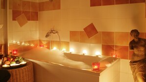 A bathroom with a bathtub, candles, and a statue. - Wörners Schloss Weingut & Wellness Hotel (Prichsenstadt)