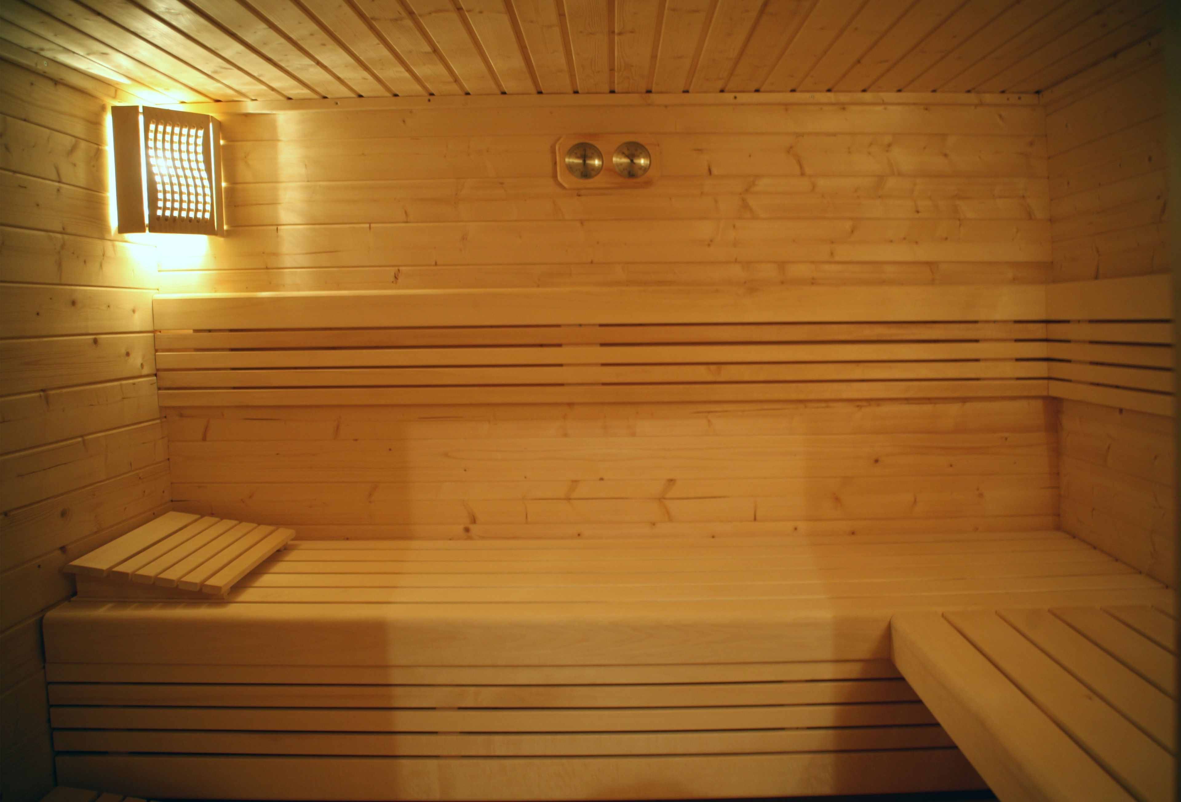 A sauna with wooden benches and a wall-mounted heater.