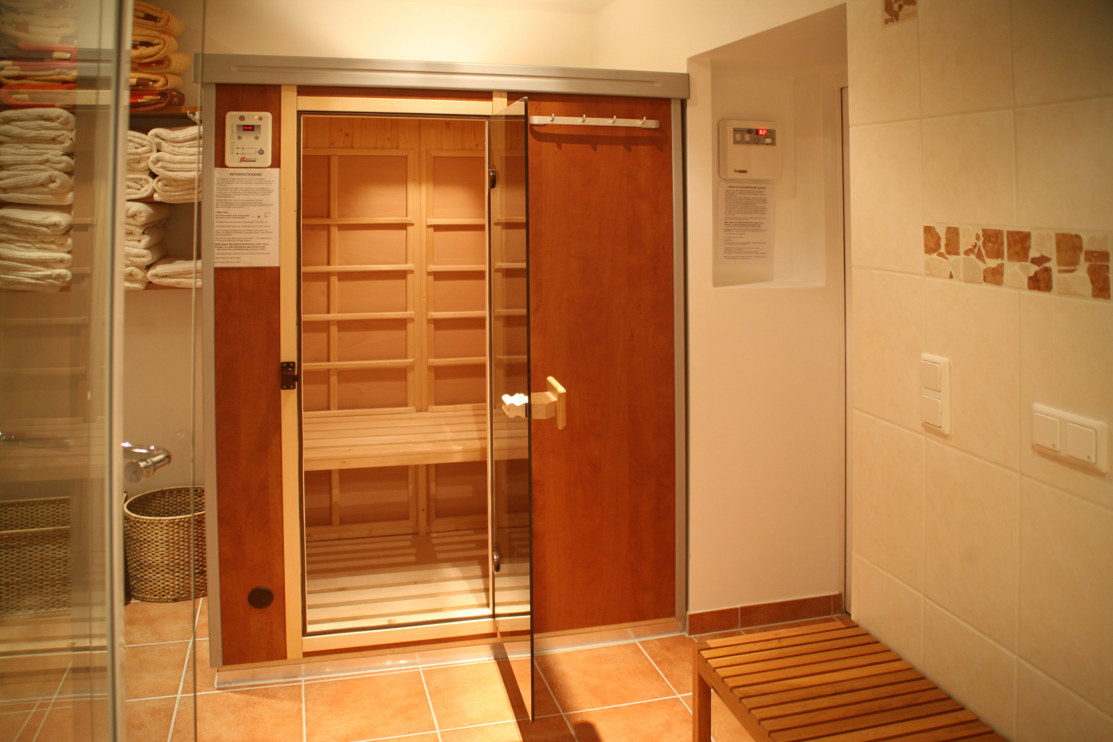 A hotel room with a sliding glass door, a wooden bench, a tiled floor, and a wall-mounted thermostat.