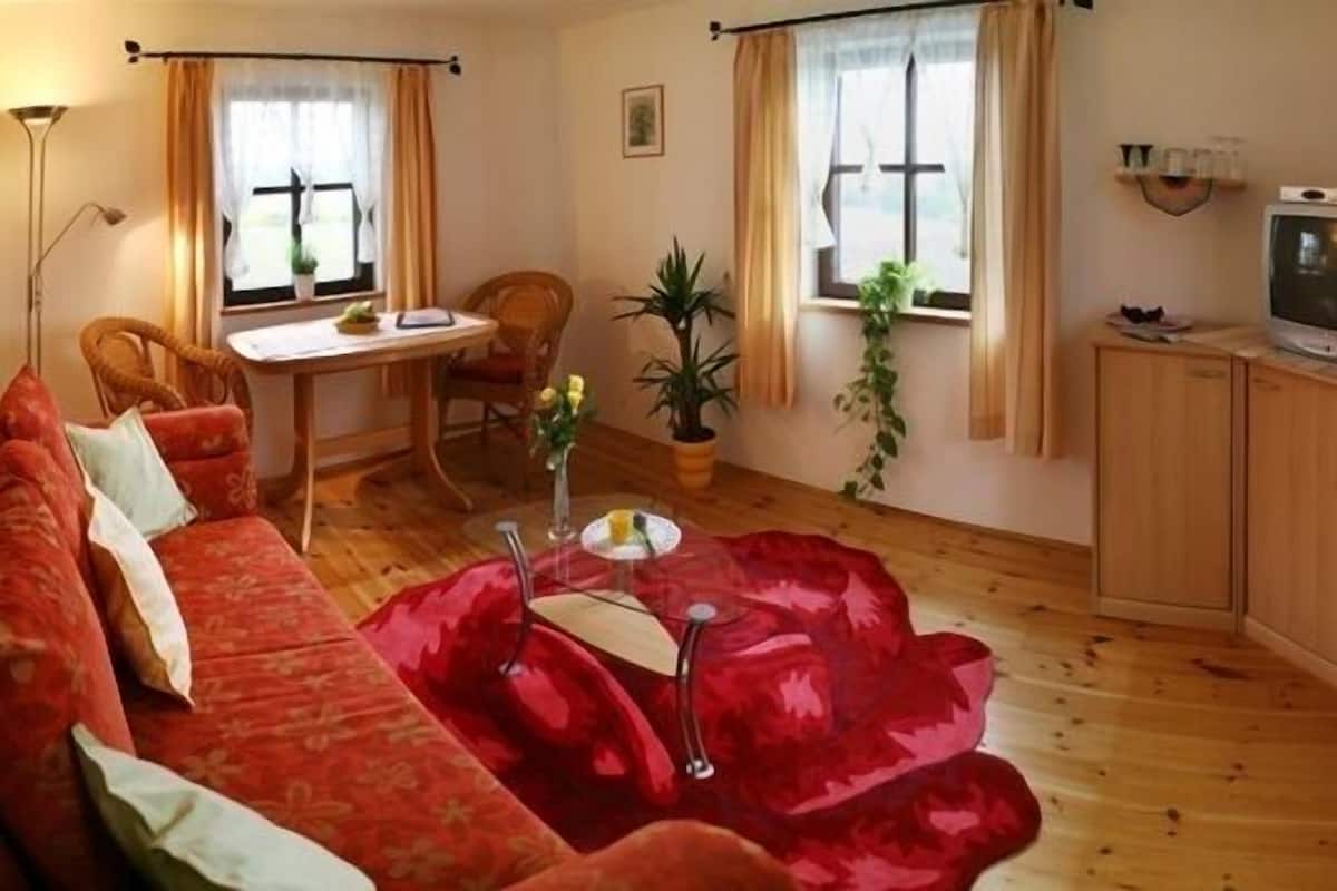 A cozy living room with a red sofa, a dining table, and a television.