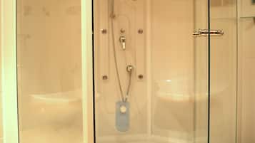 Ducha envuelta en vidrio con cabezal de ducha manual, organizador de ducha manual y grifo empotrado.