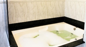 A bathtub with a black edge and a white interior, filled with bubbles.