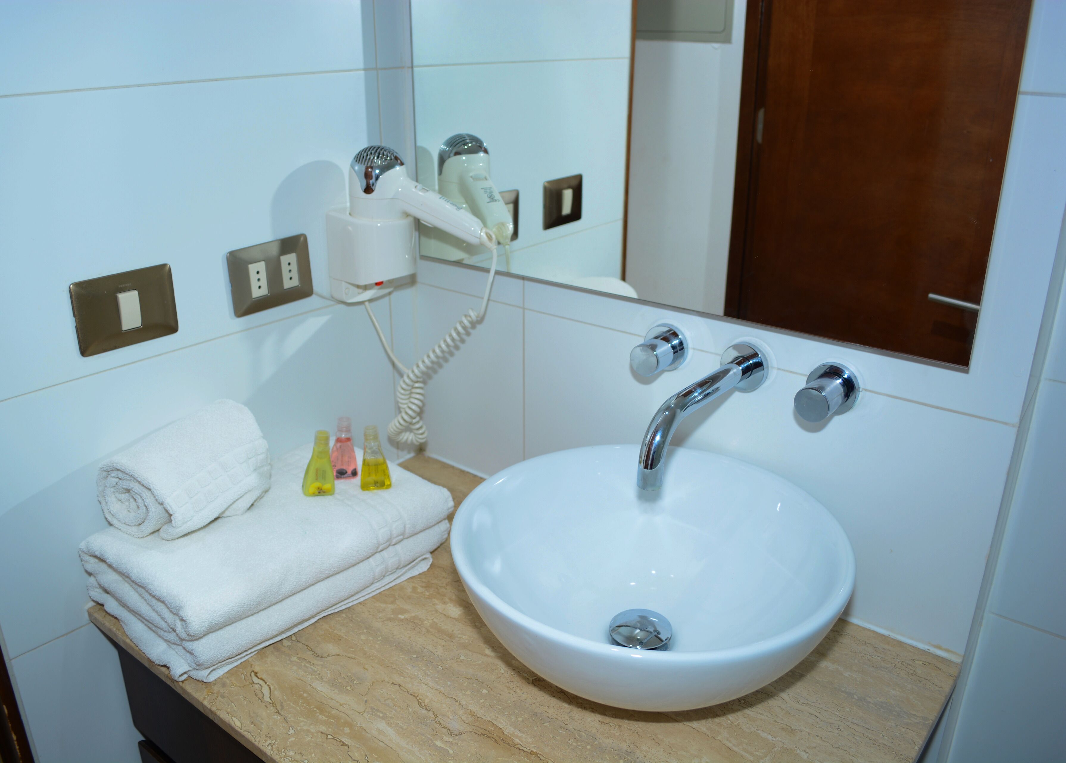 Een badkamer met een wit wastafel, een spiegel en een handdoekhouder.