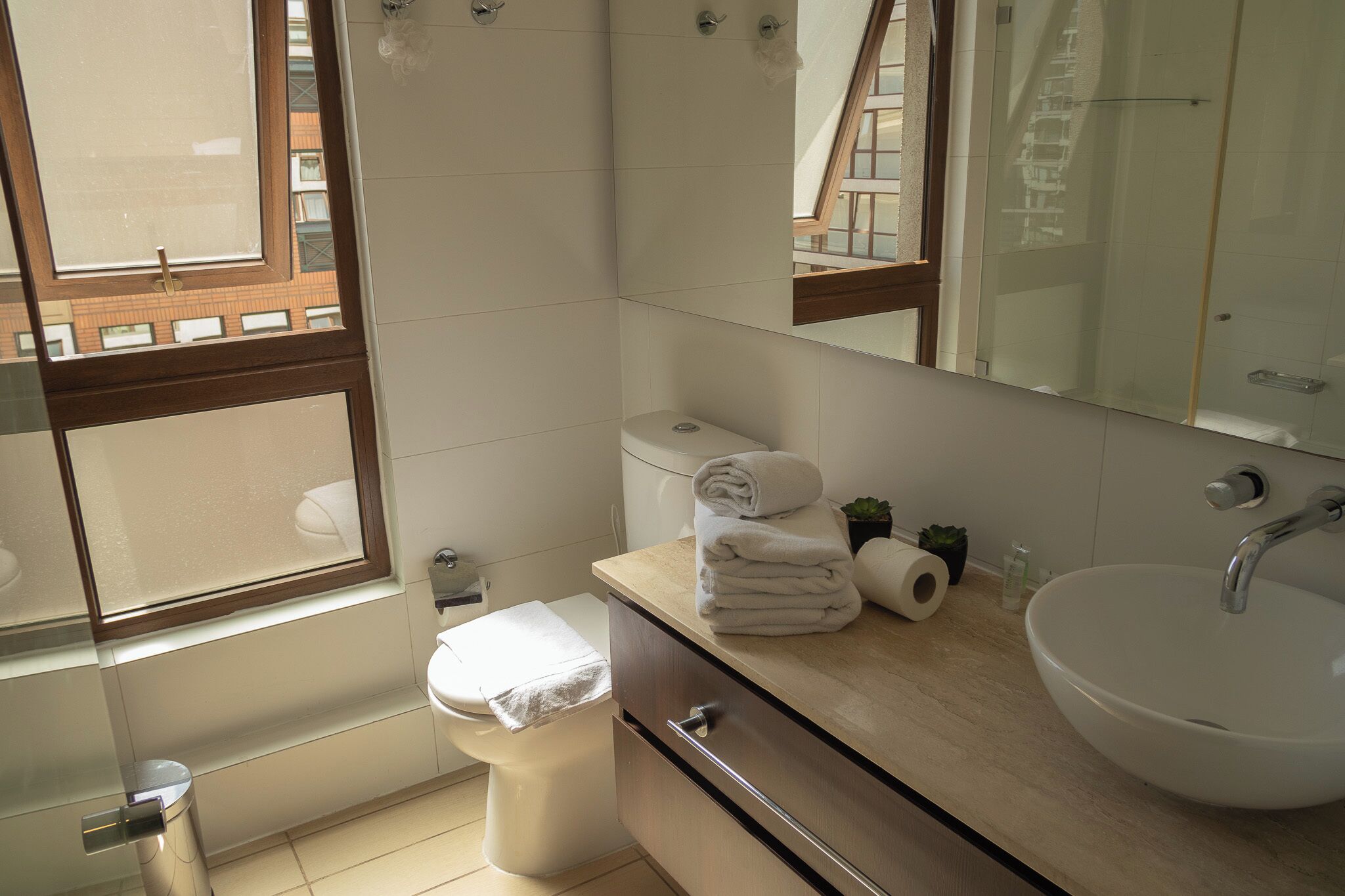 A modern bathroom with a toilet, sink, and mirror.