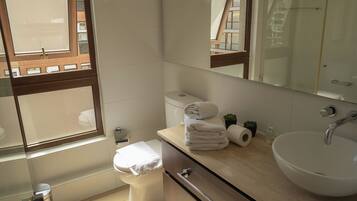 Un baño moderno con inodoro, lavamanos y espejo.