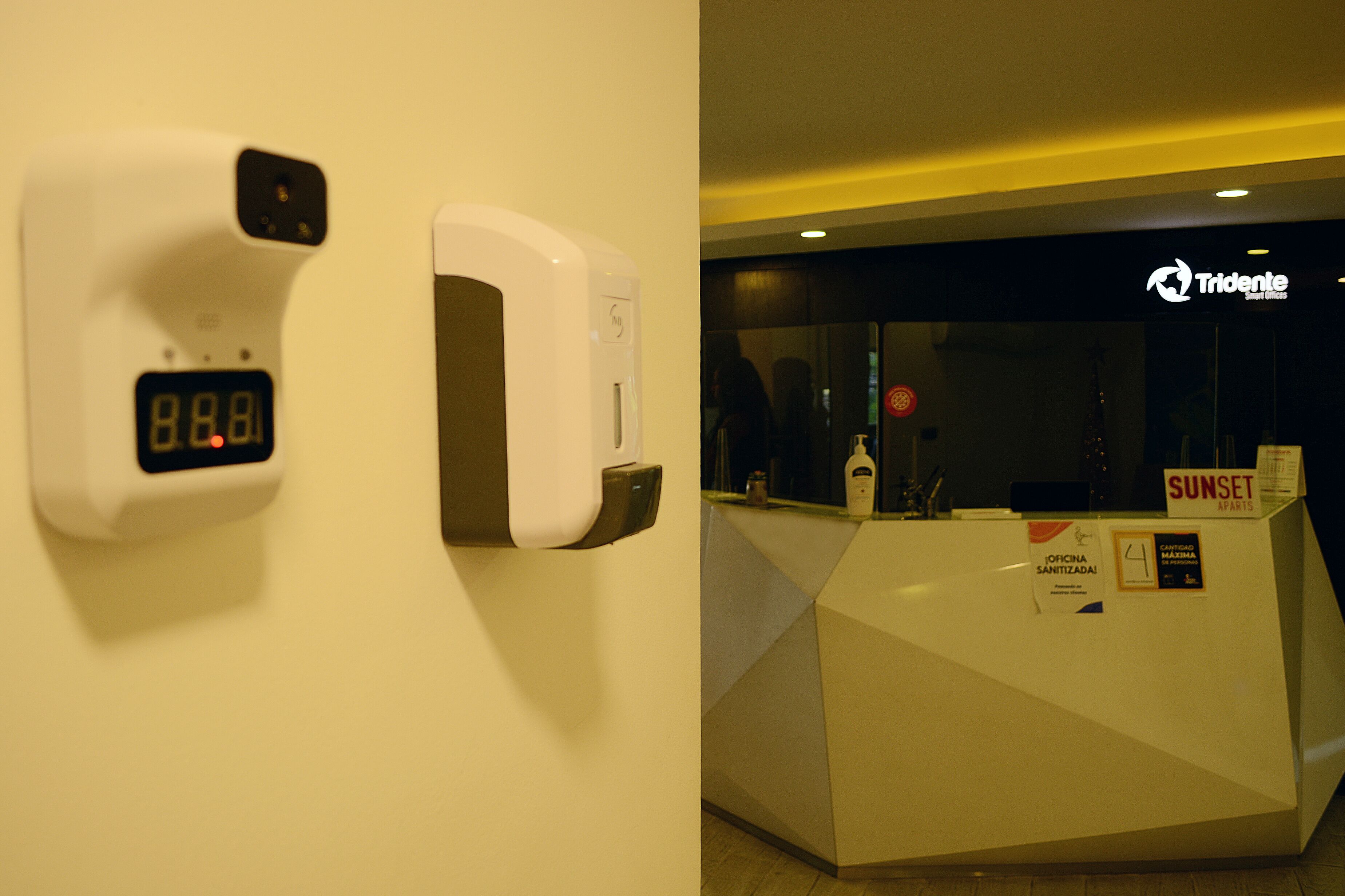 Un mostrador de recepción con un reloj digital y un cartel que dice Tridente.
