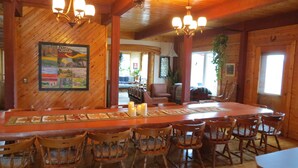 Un interior de madera con una larga mesa de comedor, sillas y una araña.