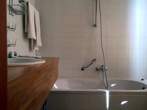 A bathroom with a wooden vanity, a sink, a bathtub, and a shower. - Hotel The New Fox (Affligem)