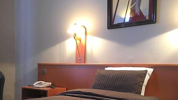 A hotel room with a bed, a nightstand, a lamp, and a mirror on the wall. - Hotel The New Fox (Affligem)