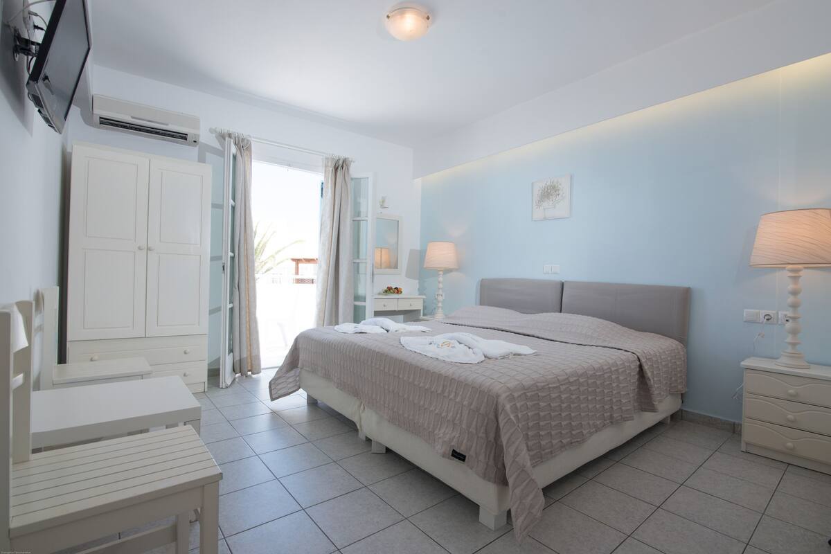 A bedroom with a bed, bedside tables, a desk, and a chair.