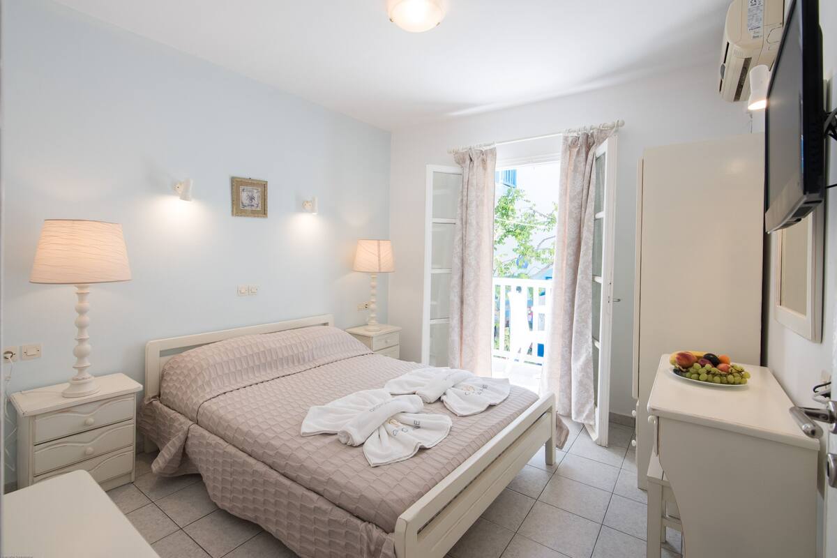 A neatly arranged bedroom with a bed, bedside tables, a dresser, and a fruit bowl.