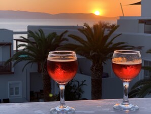 Two glasses of red beverage on a balcony with a sunset view. - Georgia Mare (Naxos)