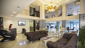 A spacious lobby with multiple seating areas, a reception desk, and a television. - Mersin Oteli (Mersin)
