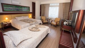 A hotel room with two beds, a desk, a chair, a television, and a window with curtains. - Mersin Oteli (Mersin)