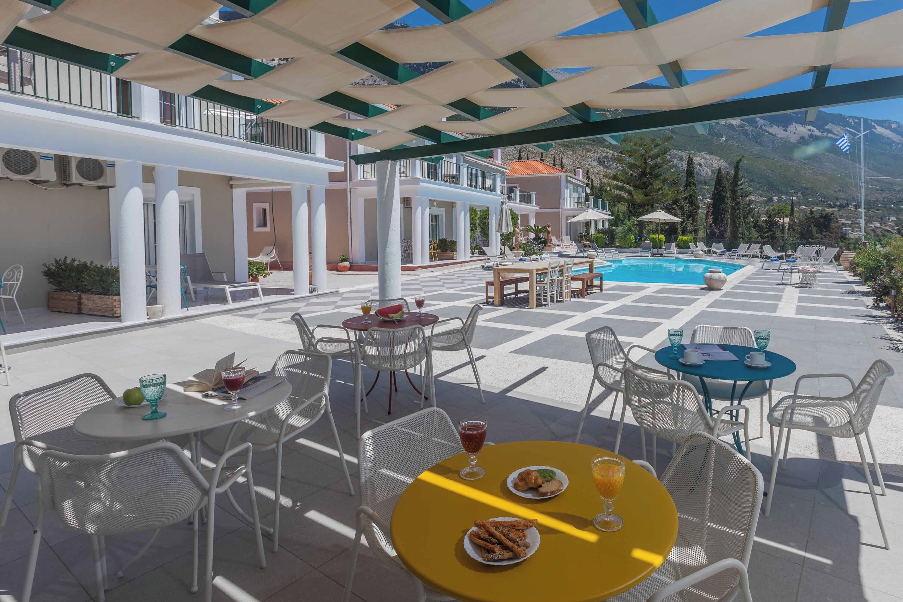 An outdoor terrace with tables and chairs, a pool, and mountain views.