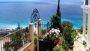 A balcony with a view of the sea, a gate, and some greenery. - Garbis Villas (Kefalonia)