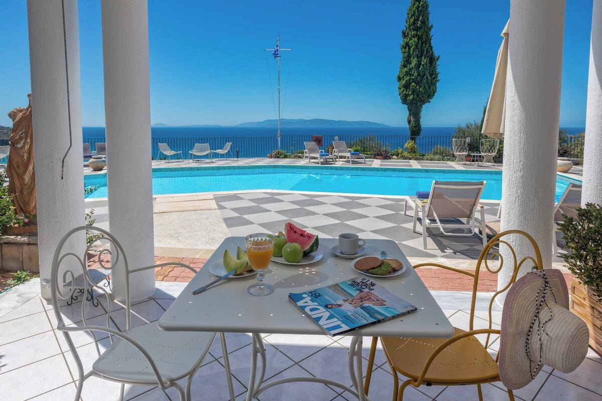 A terrace with a pool, dining table, chairs, and a magazine.