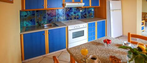 Una cocina compacta con armarios azules, estufa blanca y refrigerador.