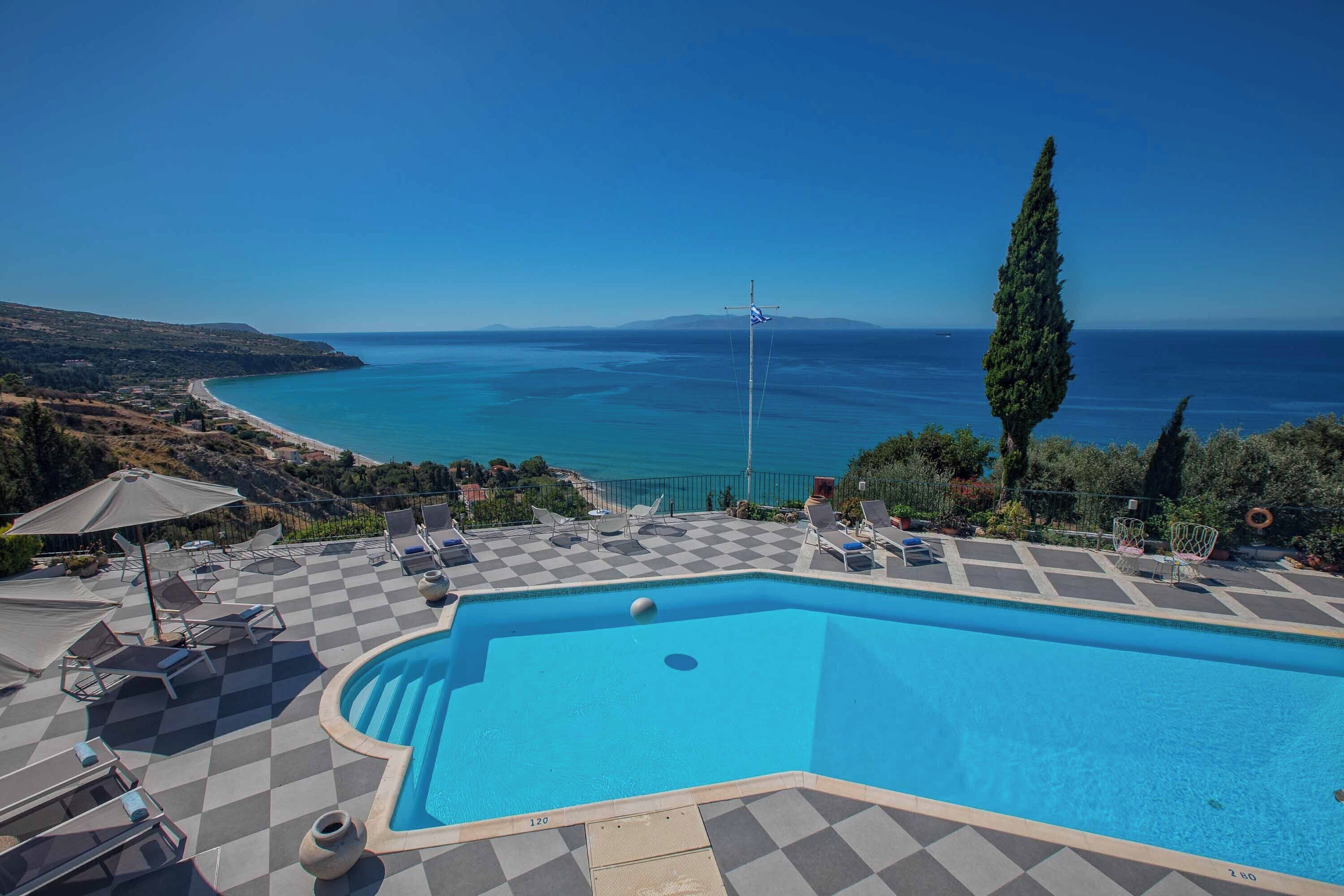 A pool with a checkered pattern, lounge chairs, and a view of the sea.