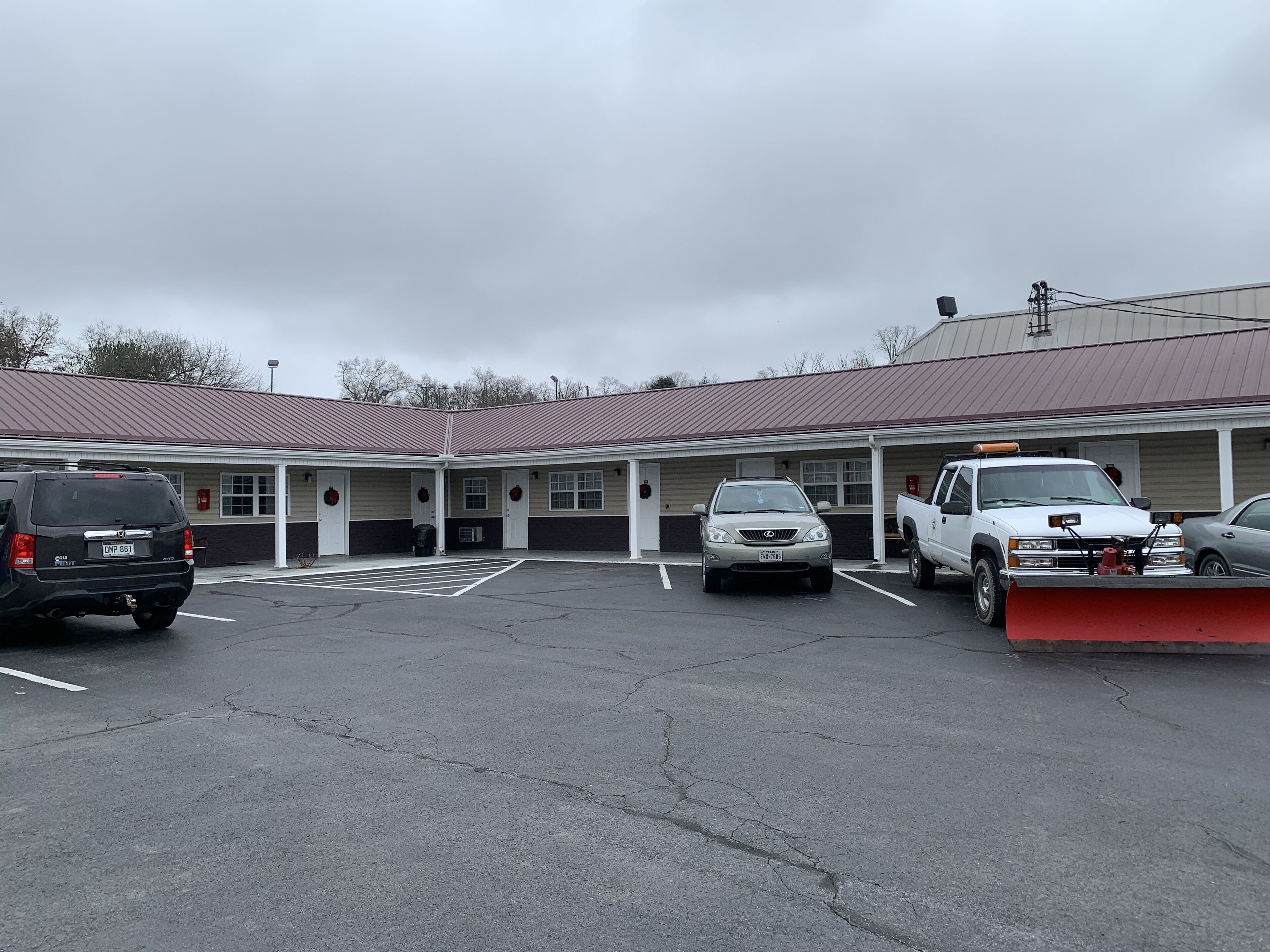 Ein Motel mit Parkplatz, ein Gebäude mit rotem Dach und ein Schneepflug davor.