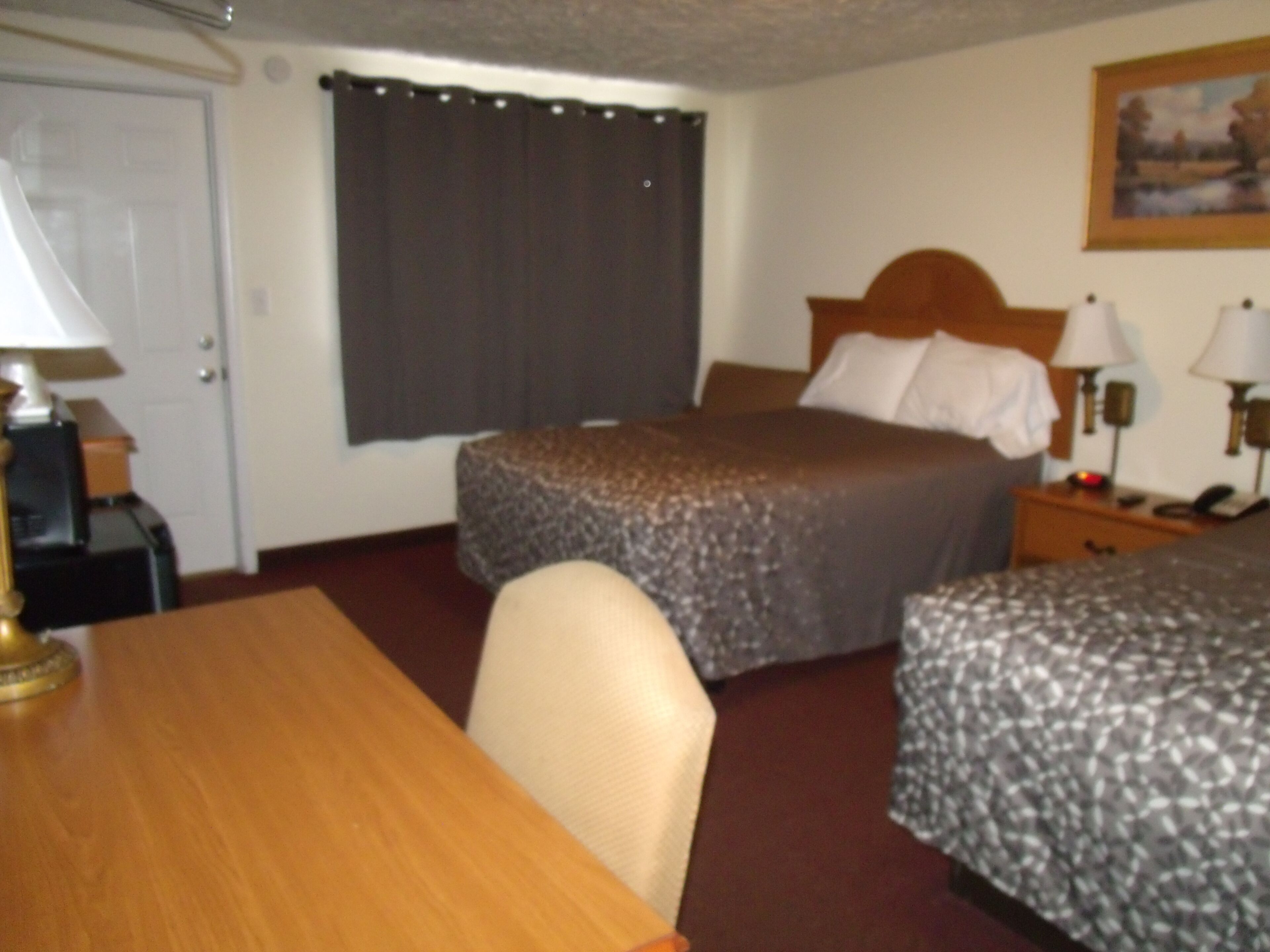A hotel room with a bed, bedside tables, a desk, and a chair.