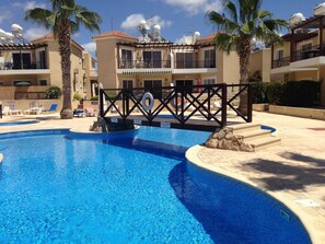 A swimming pool with a lifeguard station, lounge chairs, and palm trees. - Sirena Sunrise (Paphos)