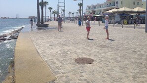 A paved promenade with a sea view, palm trees, and a few people walking. - Sirena Sunrise (Paphos)