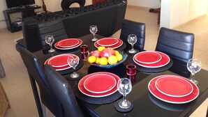 A dining table set with red plates, black chairs, and a fruit bowl. - Sirena Sunrise (Paphos)