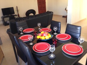 A dining table set with red plates, black chairs, and a fruit bowl. - Sirena Sunrise (Paphos)