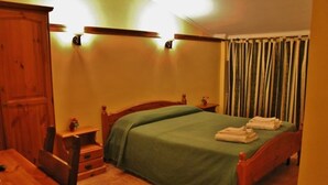 A bedroom with a wooden bed, green bedspread, and a wooden wardrobe. - Agriturismo Marco Simone (Rome)