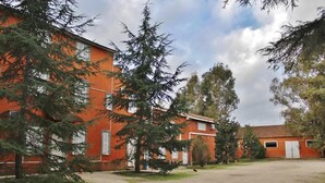 A building with a red facade, surrounded by trees and a clear sky. - Agriturismo Marco Simone (Rome)