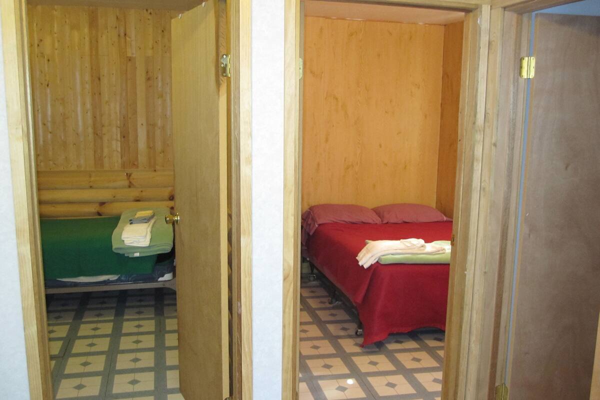 Une petite pièce, de taille modeste, comprenant un lit, une chaise verte et une petite table sur laquelle est posée une serviette pliée.