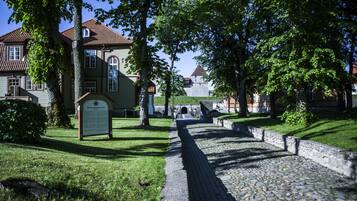 A cobblestone pathway leading to a historic building with a tiled roof and a stone wall.