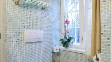 Un baño con inodoro, ventana con vistas, lavabo y espejo.