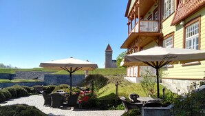 A courtyard with outdoor seating, a stone wall, and a view of a tower. - Ekesparre Boutique Hotel (Kuressaare)