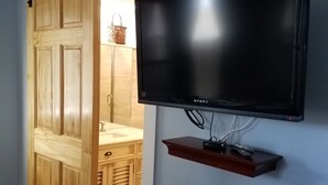 A room with a sliding barn door, a mounted flat-screen TV on a wall, and a wooden cabinet. - Tilton Inn (Tilton)