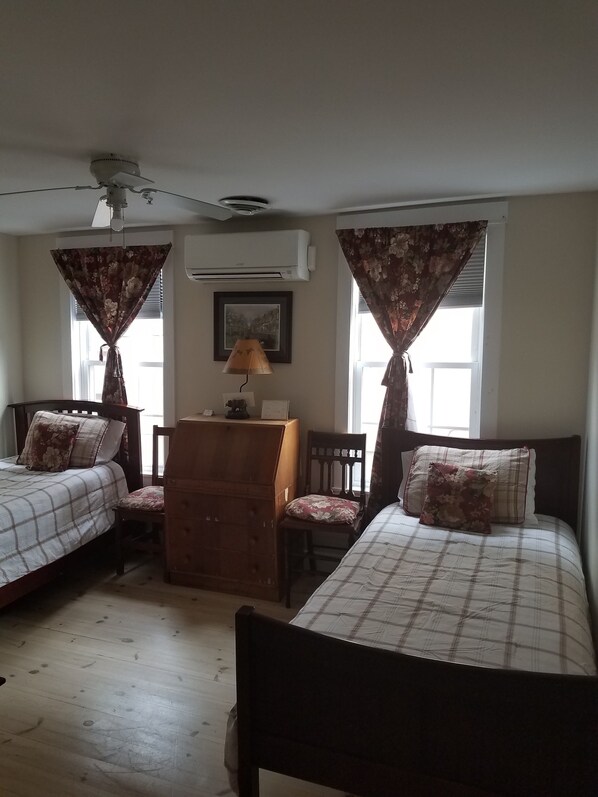 Une chambre avec deux lits, une commode, un bureau et un appareil de climatisation.