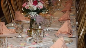 A long dining table set with pink napkins, clear glassware, and floral centerpieces. - Tilton Inn (Tilton)