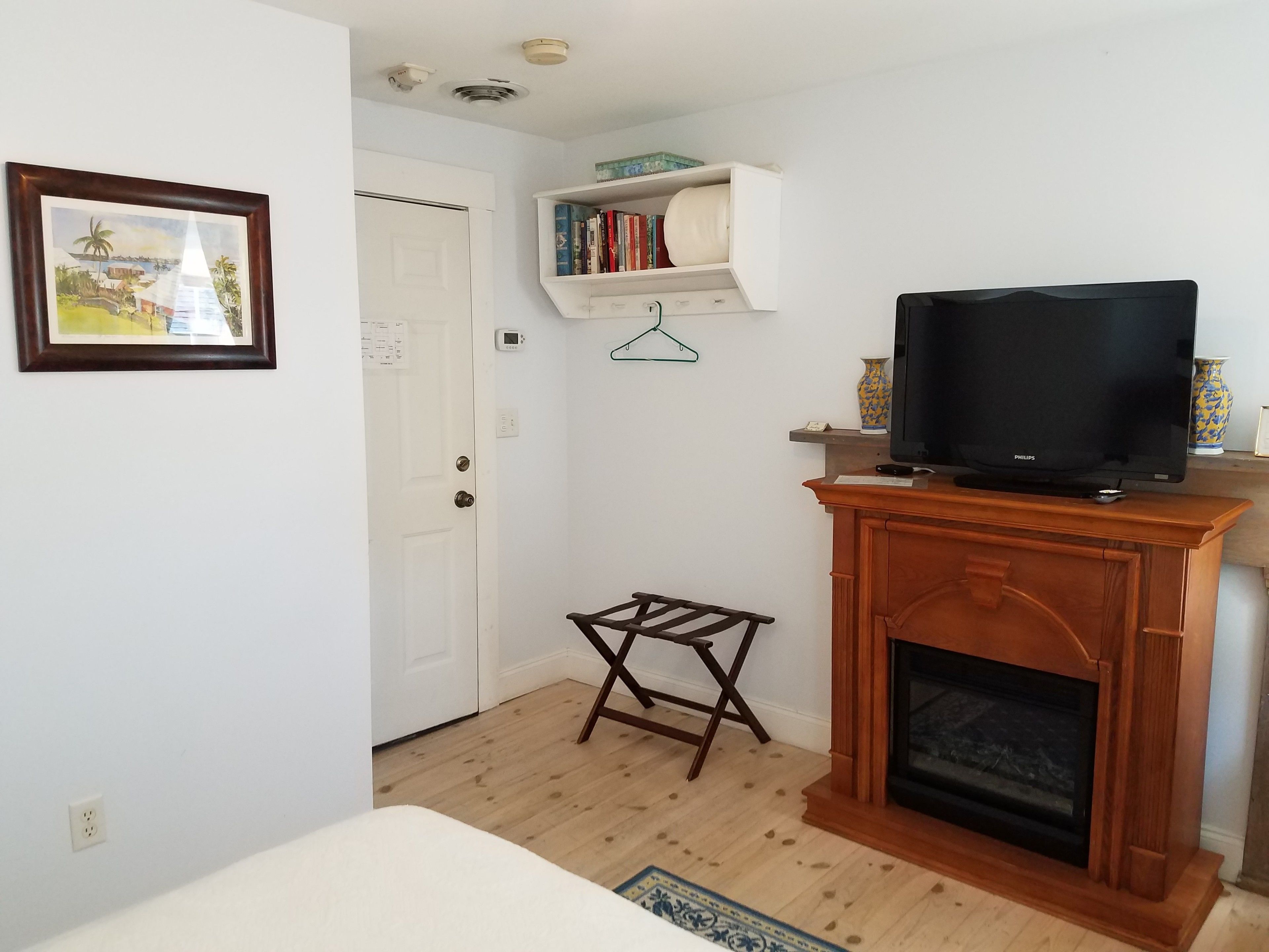 Una sala de estar con chimenea, televisor, estantería y una pequeña mesa de madera.