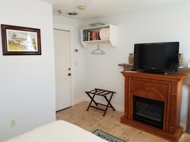 Una sala de estar con chimenea, televisor, estantería y una pequeña mesa de madera.