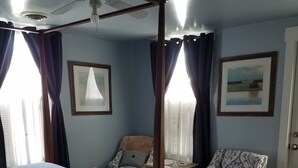A bedroom with a four-poster bed, a chair, a small table, and a ceiling fan. - Tilton Inn (Tilton)