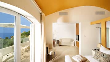 Una habitación de hotel moderna con balcón, un sofá, un televisor y un área de comedor.