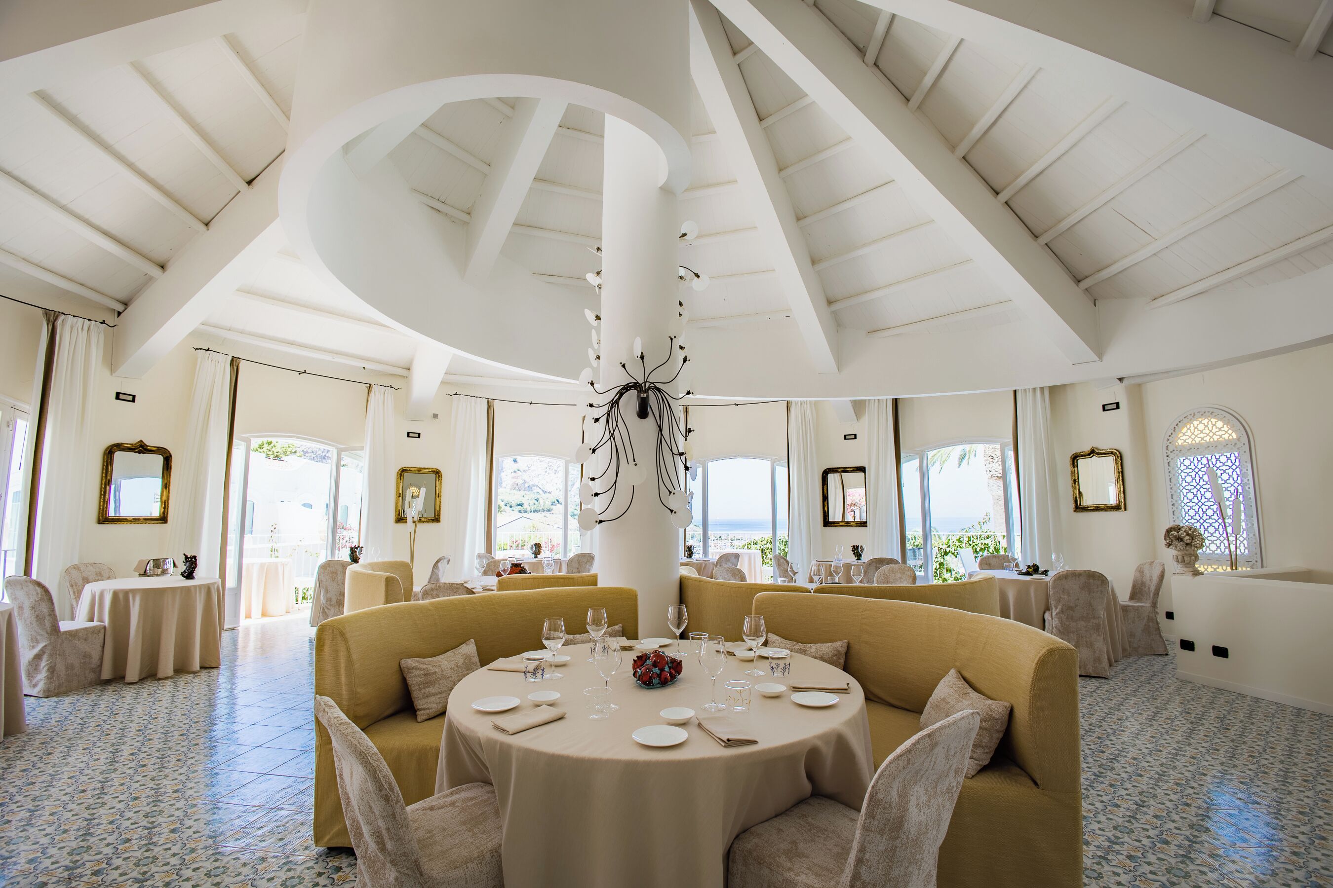 A spacious room with a high ceiling, a central round table set for dining, and comfortable seating.