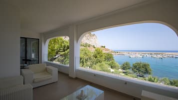 Amplia sala de estar con un ventanal que ofrece vistas a un puerto deportivo y al paisaje costero.