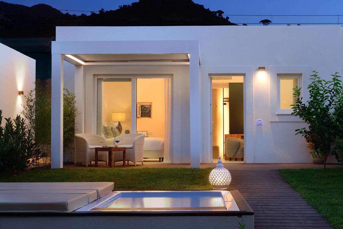 A modern house with a well-lit patio, a pool, and a garden.