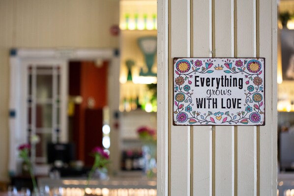 A sign with floral designs and the text "Everything grows with love" on a white wall.