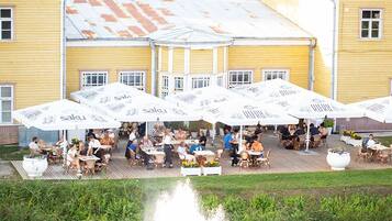 Een buiten eetgedeelte met meerdere witte parasols met daarop de tekst