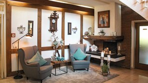 A cozy living room with two armchairs, a floor lamp, a fireplace, and a staircase. - Hotel Stockhausen GbR (Schmallenberg)