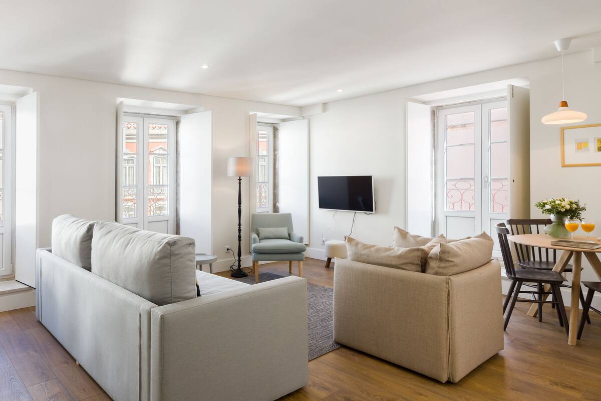 A modern living room with a sofa, armchair, and dining table with chairs.
