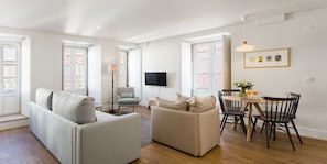 A modern living room with a sofa, armchair, and dining table with chairs. - LSA Bairro Alto by Numa (Lisbon)
